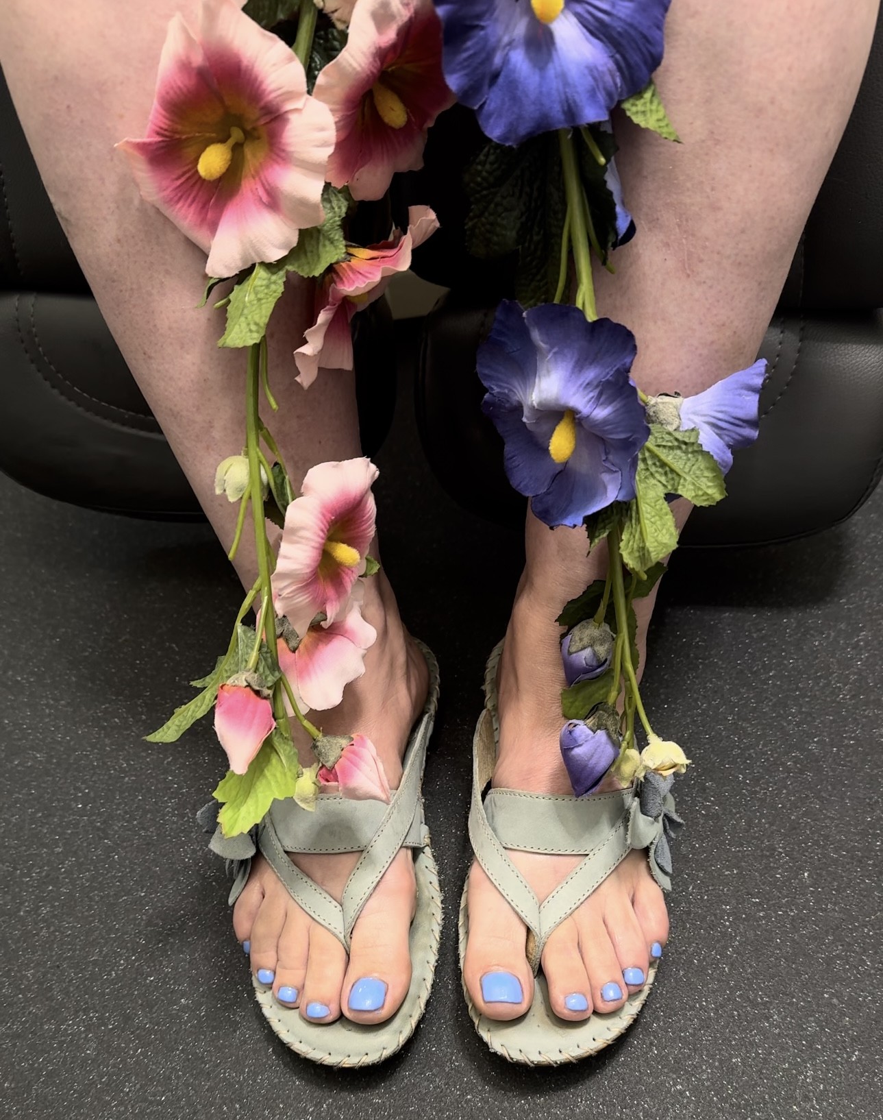 Lichtblauwe nagellak, voeten in sandalen met stokrozen en viooltjes